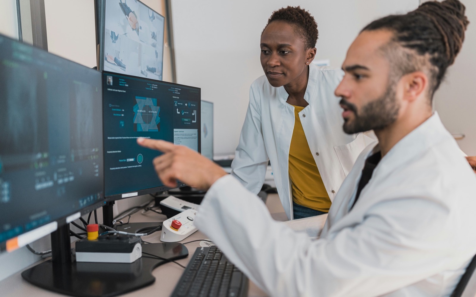 Two clinicians reviewing digital medical imaging at a multi-monitor workstation